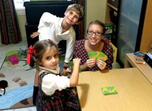 Language Assistant playing cards with her host siblings